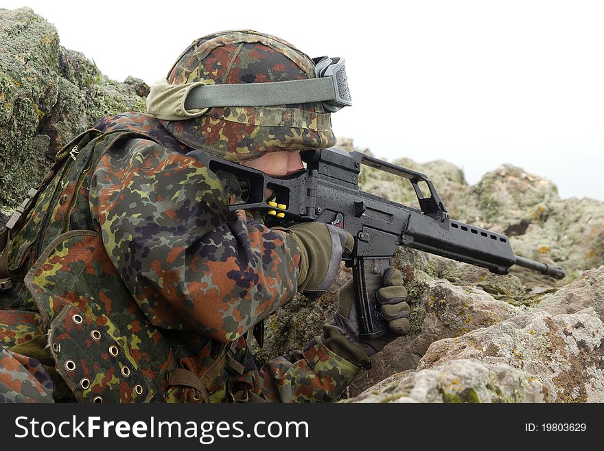 Young warrior hiding behind the rock with a gun. Young warrior hiding behind the rock with a gun