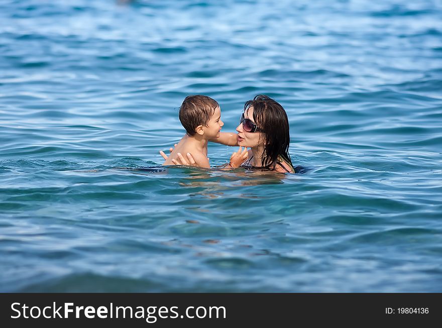 Joyful mother and son swimming in sea