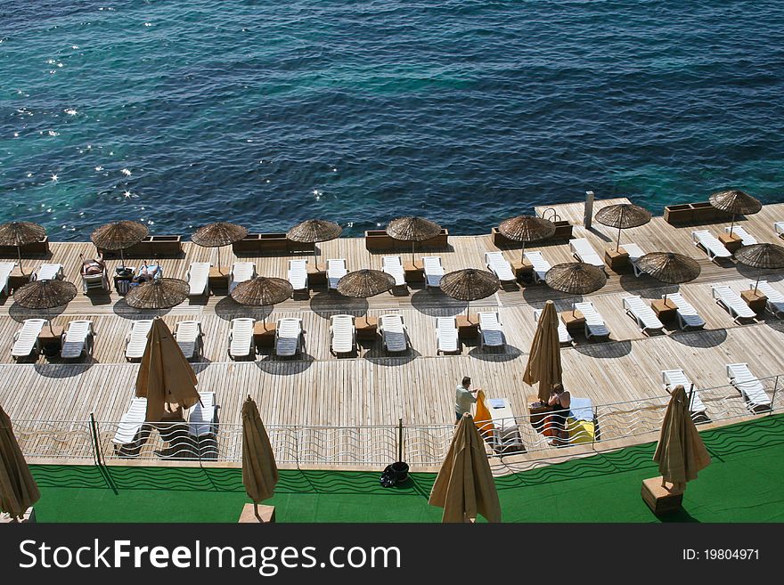 Platform with umbrellas and seats on the aegean sea shore.