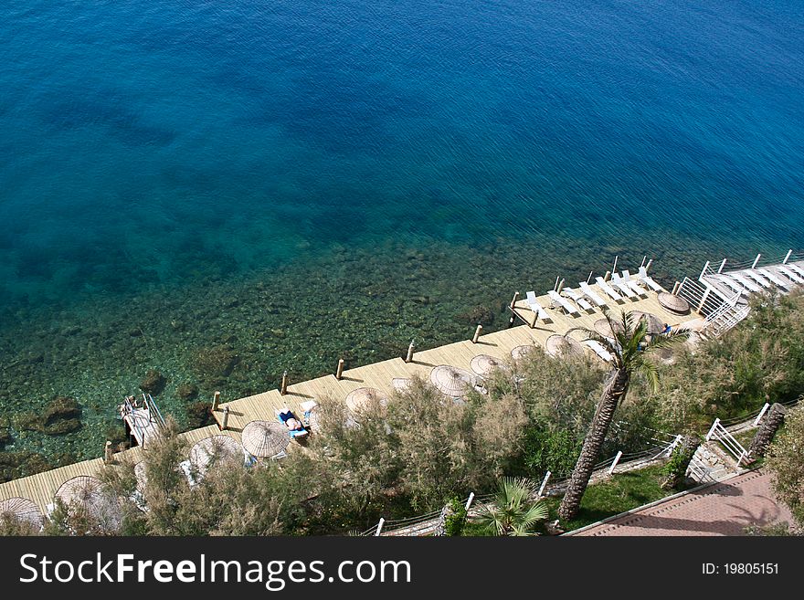 Platform with umbrellas and seats on the aegean sea shore.