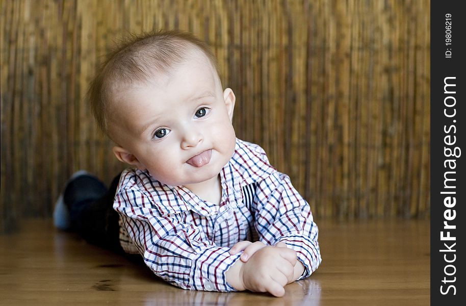 The small cheerful kid lie on a floor.