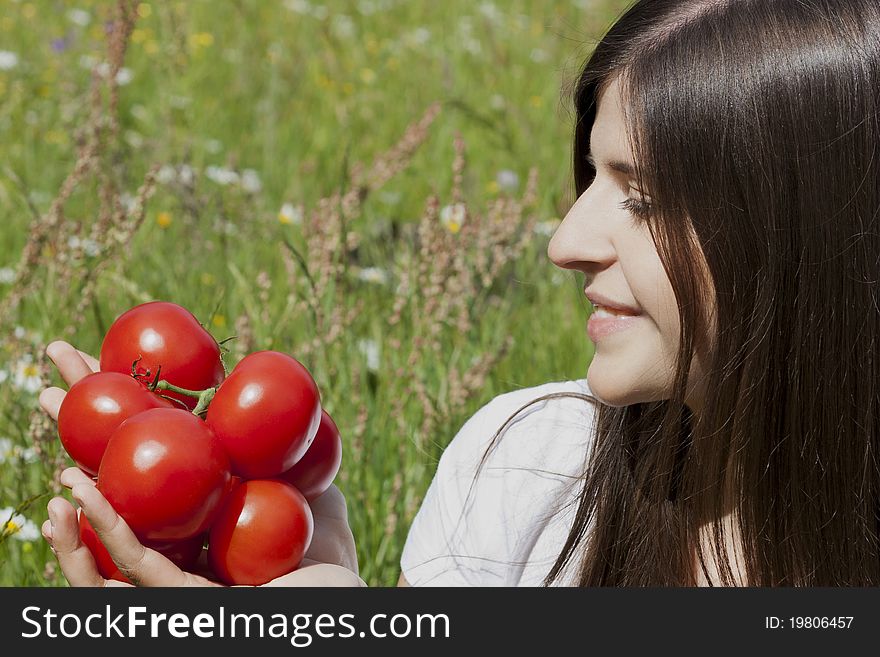 Portrait of a pretty teenage girl holding tomatoes and smiling