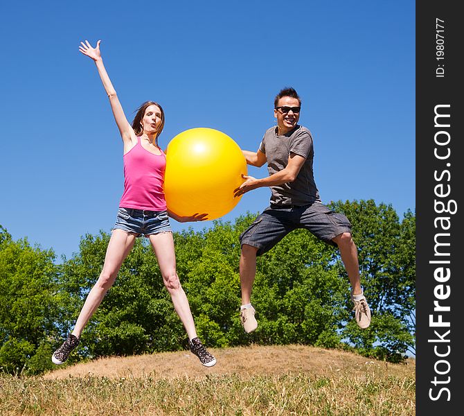 Two young people play with big yellow ball in park. Two young people play with big yellow ball in park