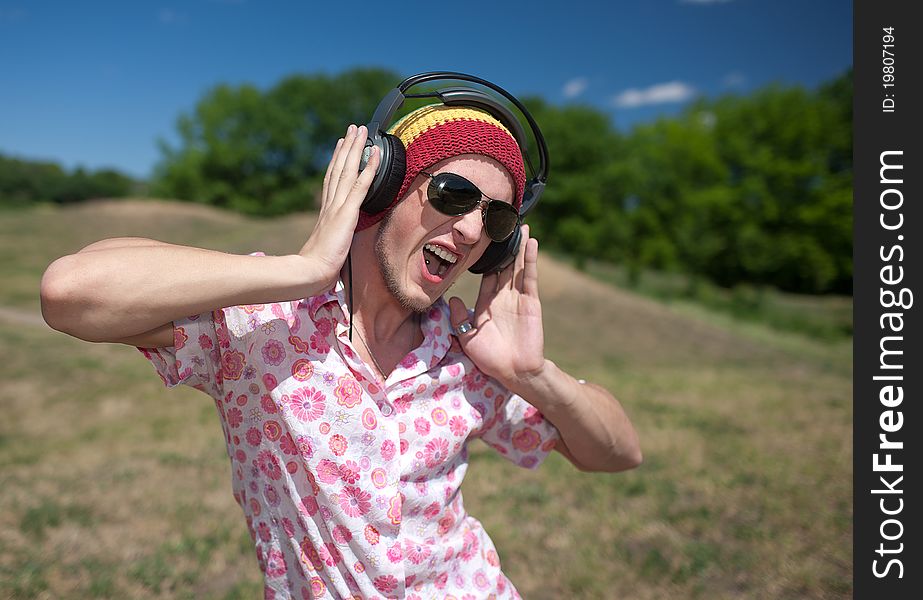 Young man in glasses with headphones in park. Young man in glasses with headphones in park