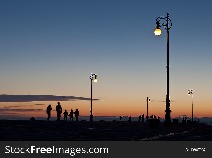 Silhouettes of people walking on pier in Trieste. Silhouettes of people walking on pier in Trieste.