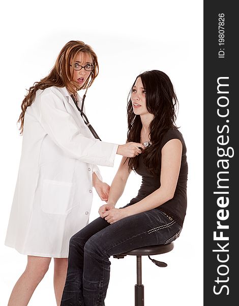 A women doctor checking her patients heart beat with a shocked expression on her face. A women doctor checking her patients heart beat with a shocked expression on her face.