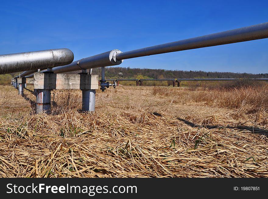 The high pressure pipeline in a summer landscape with the dark blue sky. The high pressure pipeline in a summer landscape with the dark blue sky