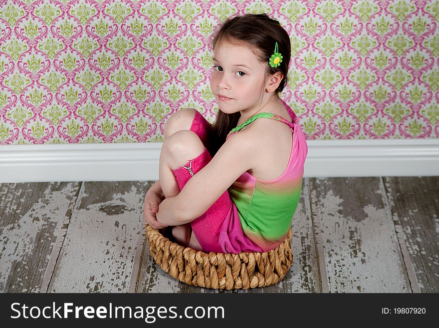 Cute girl sitting in basket on the old-fashion floor. Cute girl sitting in basket on the old-fashion floor