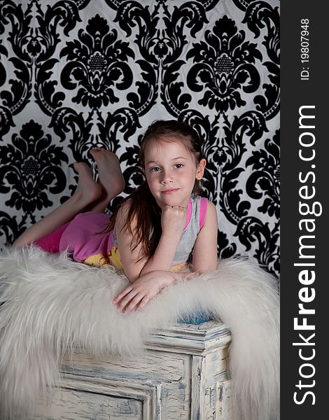 Portrait of cute girl laying on the old fashion box over the black & white background