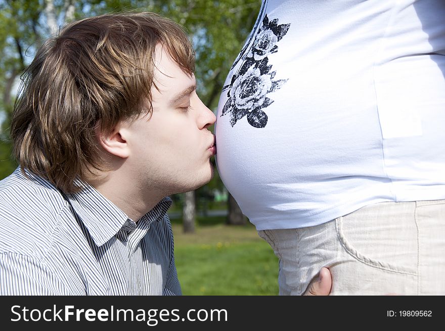 Man kisses his wife's belly. Man kisses his wife's belly