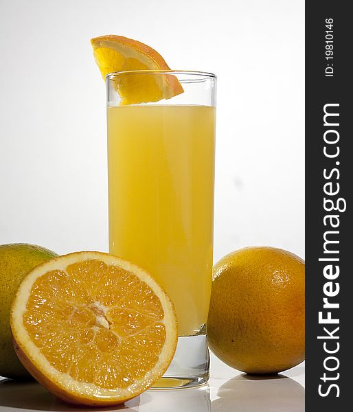 Glass of orange juice with sliced oranges on a table