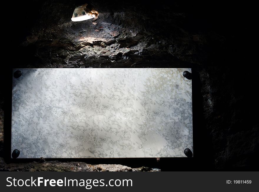 Marble sign enlighted by lamp in cave