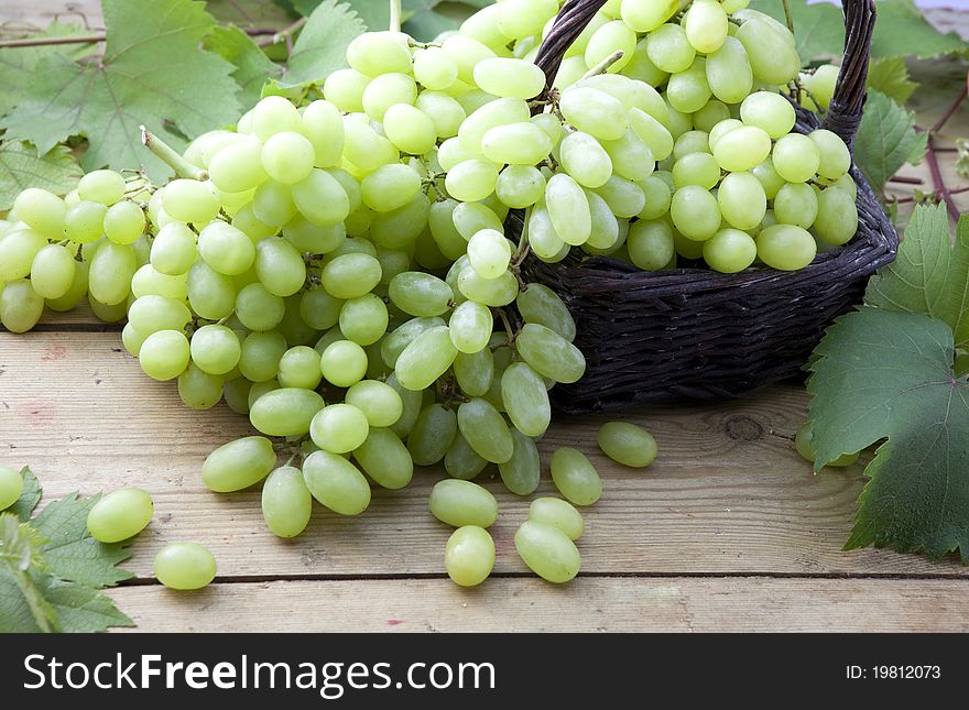 White grapes in wicker basket on a rustic wooden table