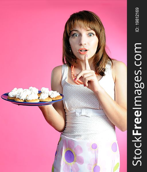 Young woman with cookies on pink background