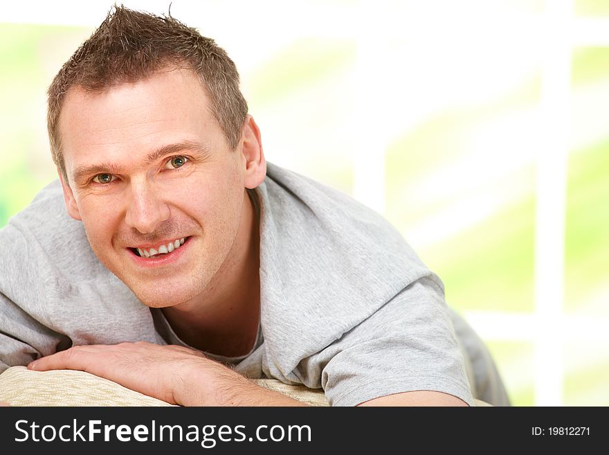 Portrait of a cheerful man relaxing on sofa at home. Indoors, horizontal color image