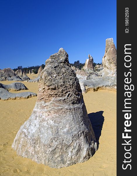 A conical, limestone pinnacle rises from the desert sand. A conical, limestone pinnacle rises from the desert sand.