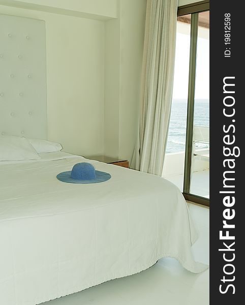 Modern room in white color with blue hat on the bed. Modern room in white color with blue hat on the bed