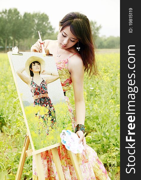 Young female artist with her oil painting in field.