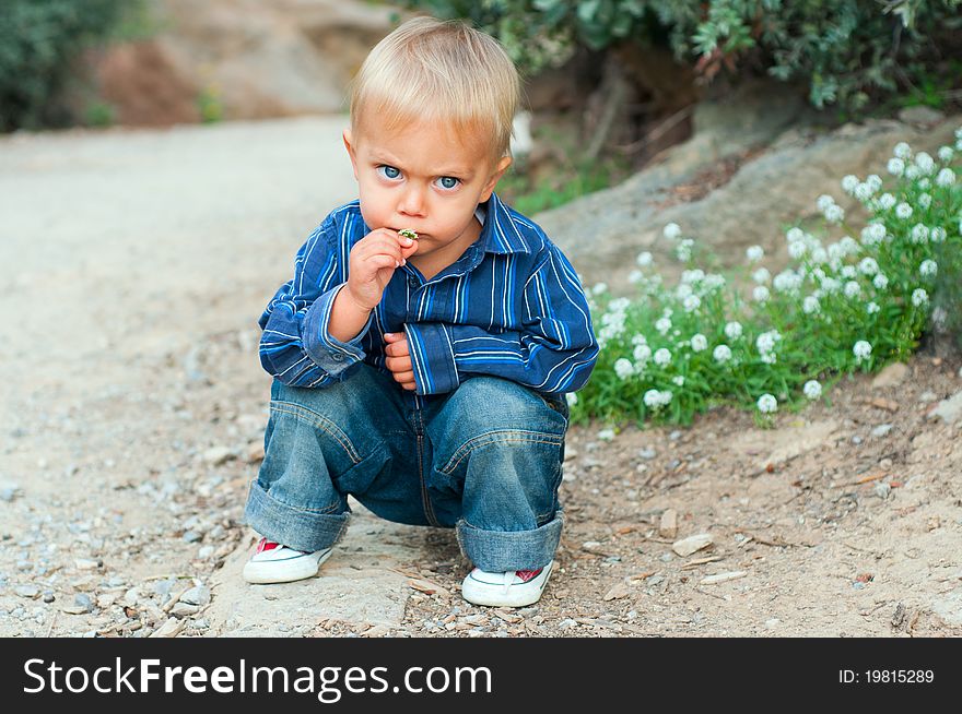 Cute 2 years old boy sitting on the footpath in the park. Cute 2 years old boy sitting on the footpath in the park