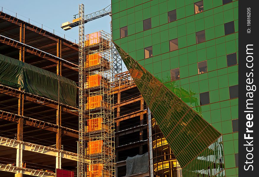 Part of the pacific design center under construction with huge crane against blue sky at sunset. Part of the pacific design center under construction with huge crane against blue sky at sunset.