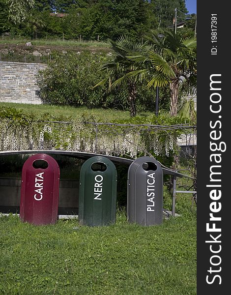 Three containers for recycling in a park.