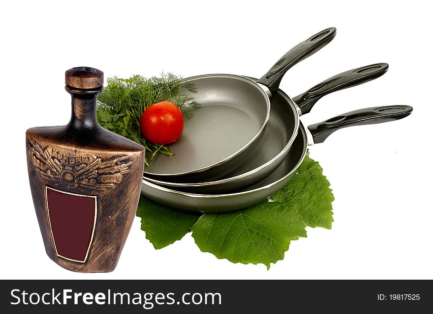 Three frying pens,greens,tomato and ceramic vessel. Three frying pens,greens,tomato and ceramic vessel.