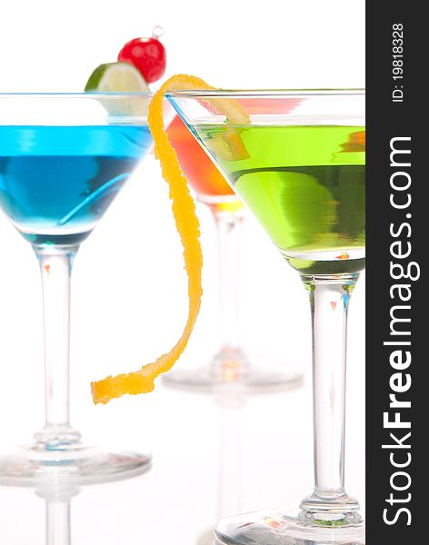 Summer Tropical Martini Cocktails with vodka, apple and peach liqueur, pineapple and cranberry juice, lime, lemon, blue curacao, maraschino cherry in cocktail glass isolated on a white background