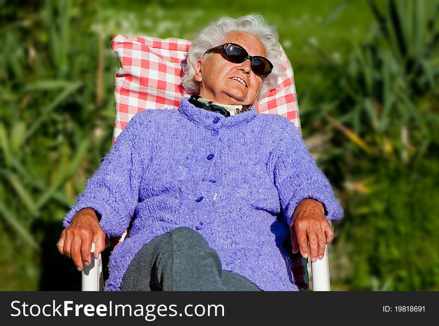 Senior woman has a rest in a chair-bed.