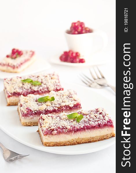 Raspberries cheesecake bars on white plate on white background