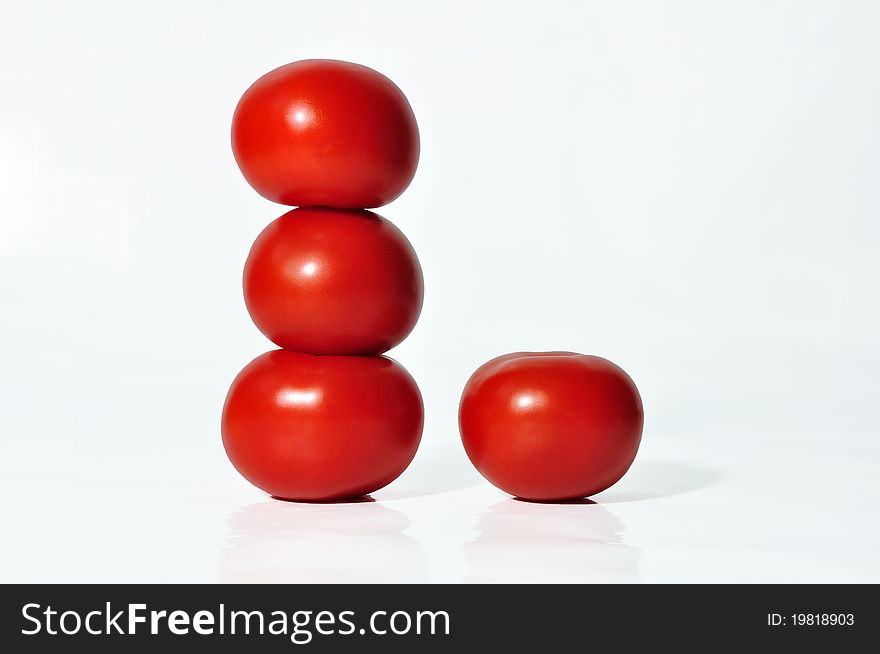 Four tomatoes on a white background in a tower.