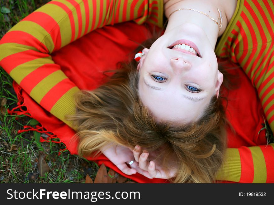 Portrait of a girl in a bright colored striped sweater lying on the grass. Portrait of a girl in a bright colored striped sweater lying on the grass