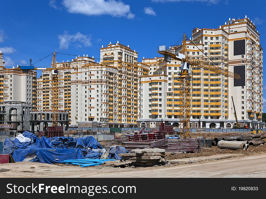 Construction site multi-storey complex with construction cranes on blue sky background. Construction site multi-storey complex with construction cranes on blue sky background.