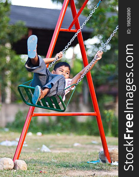 Young asian boy playing swing at playground