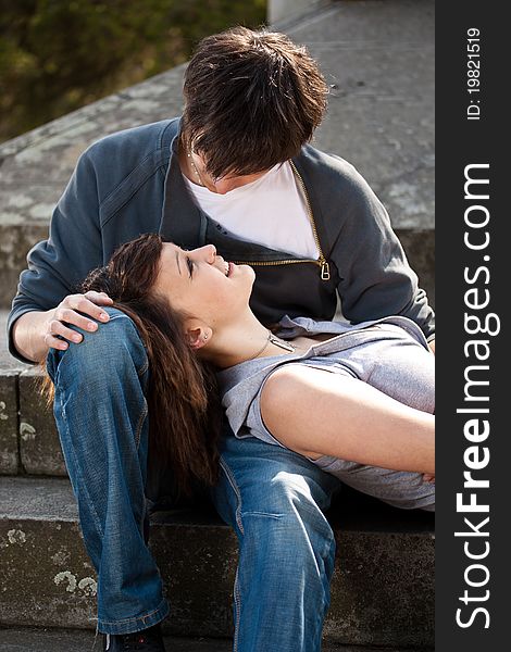 Portrait of young love couple sitting together on steps of a building