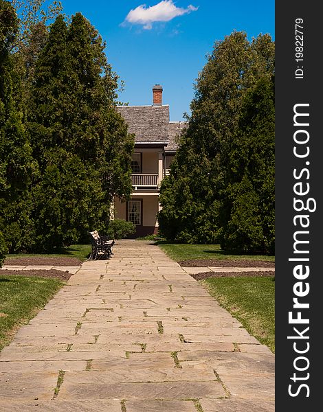 A stone pathway with a bench and house in background