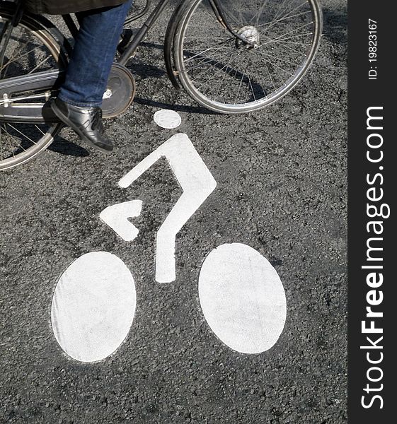 Cyclist sign painted on the road, a bicycle passing by. Cyclist sign painted on the road, a bicycle passing by