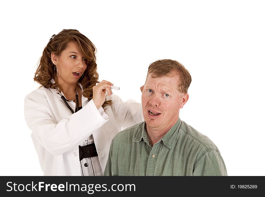 A women doctor checking her patients ear by using a light. They both have shocked expressions on their faces. A women doctor checking her patients ear by using a light. They both have shocked expressions on their faces.