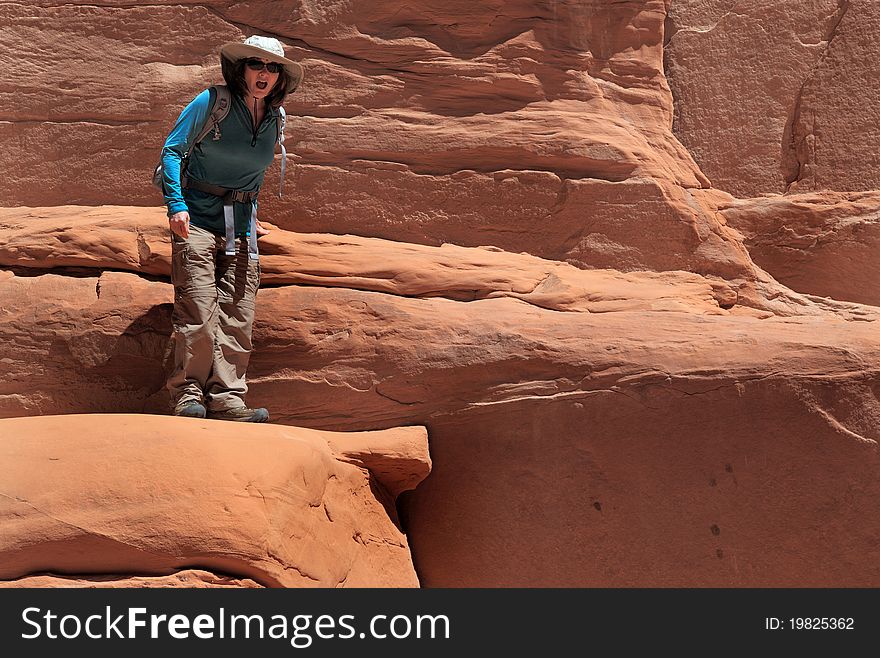 Woman hiker considers the fall potential in Arches National Park. Woman hiker considers the fall potential in Arches National Park