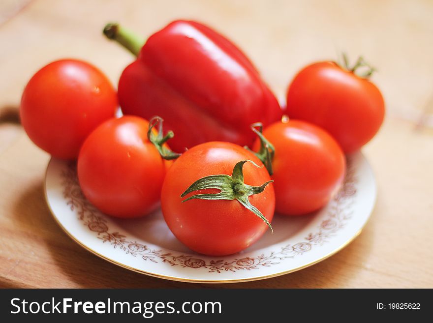 Tomatoes and red peppers on a white plate with gold rim