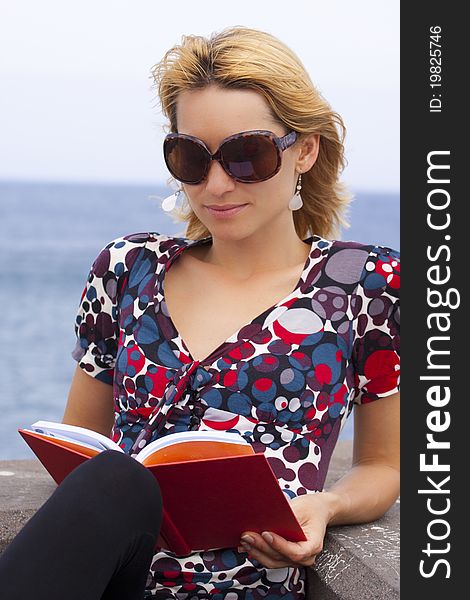 Attractive young lady reading a book by the sea. Attractive young lady reading a book by the sea.