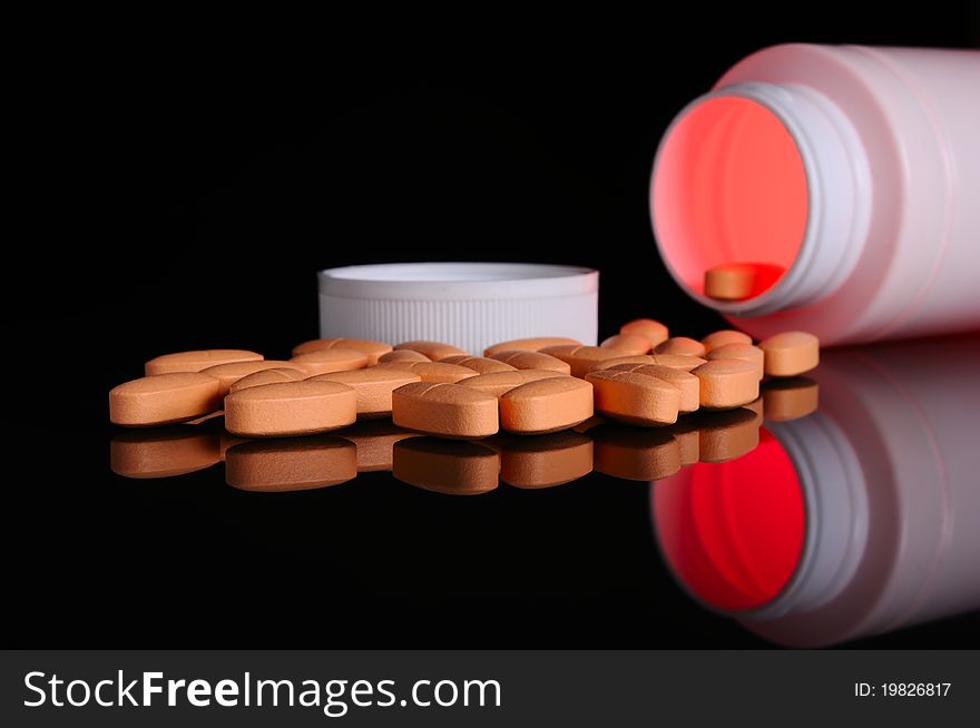 Pill bottle with orange pills on black