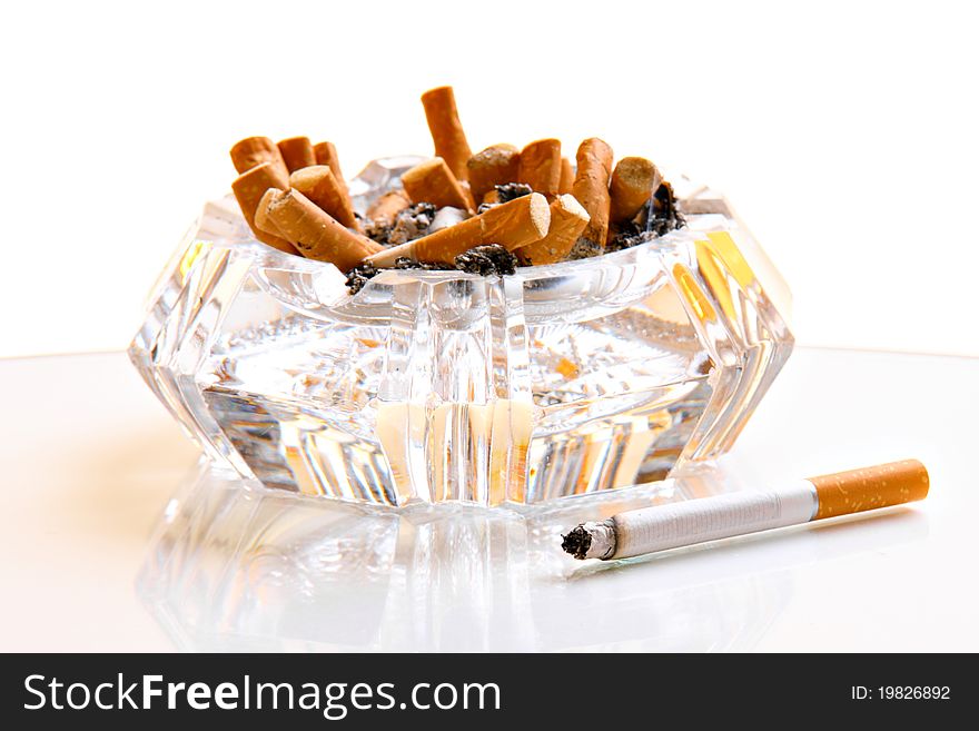 Many cigarettes in glass ashtray, isolated on white