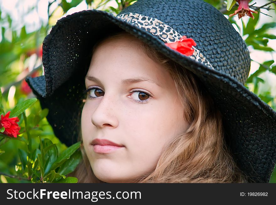 Portrait of teen girl in a black hat against the backdrop of the garden. Portrait of teen girl in a black hat against the backdrop of the garden.