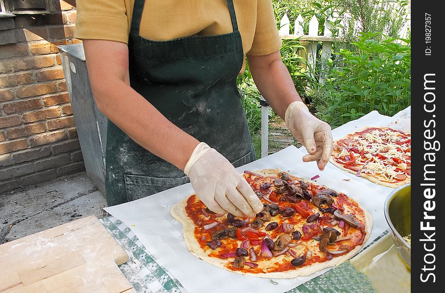 Adding toppings to organic pizza at outdoor market. Adding toppings to organic pizza at outdoor market