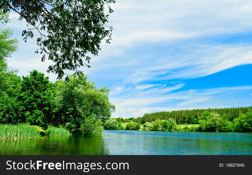 Shows the river, trees, grass and sky.