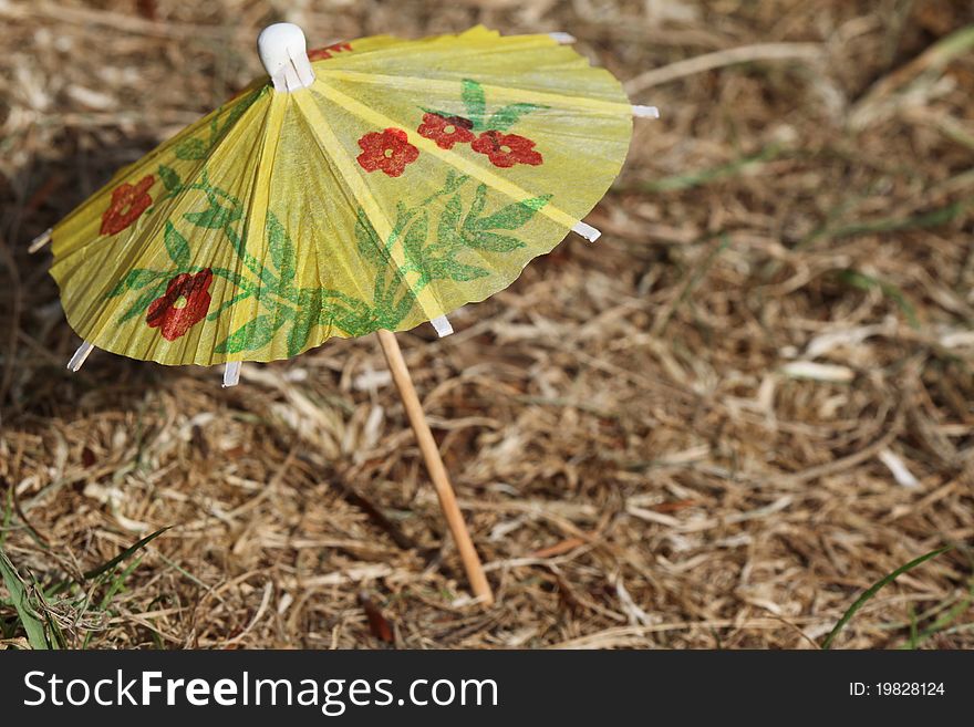 It is a small umbrella fixed in a dry grass. It is a small umbrella fixed in a dry grass.