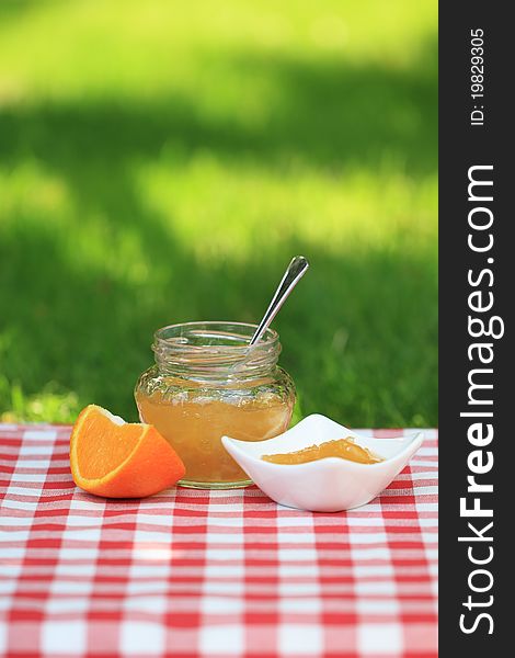 Jar of orange jam on the table in the summer garden