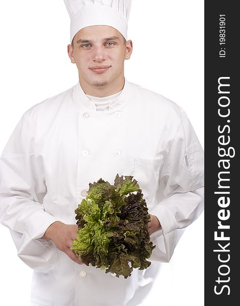 The young chef in uniform and chef's hat holding a lettuce leaf.