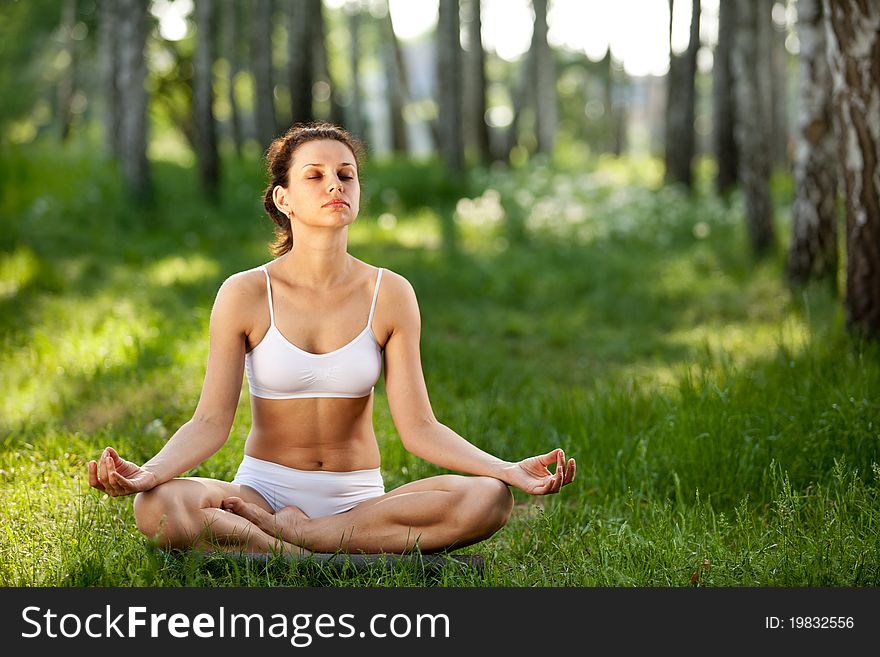 Practicing of yoga outdoors. Woman sitting in lotus pose.