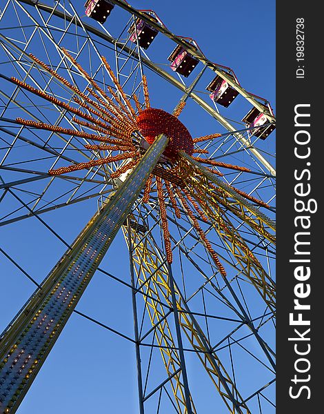 Attraction - a Ferris wheel on the background of clear blue sky. Attraction - a Ferris wheel on the background of clear blue sky